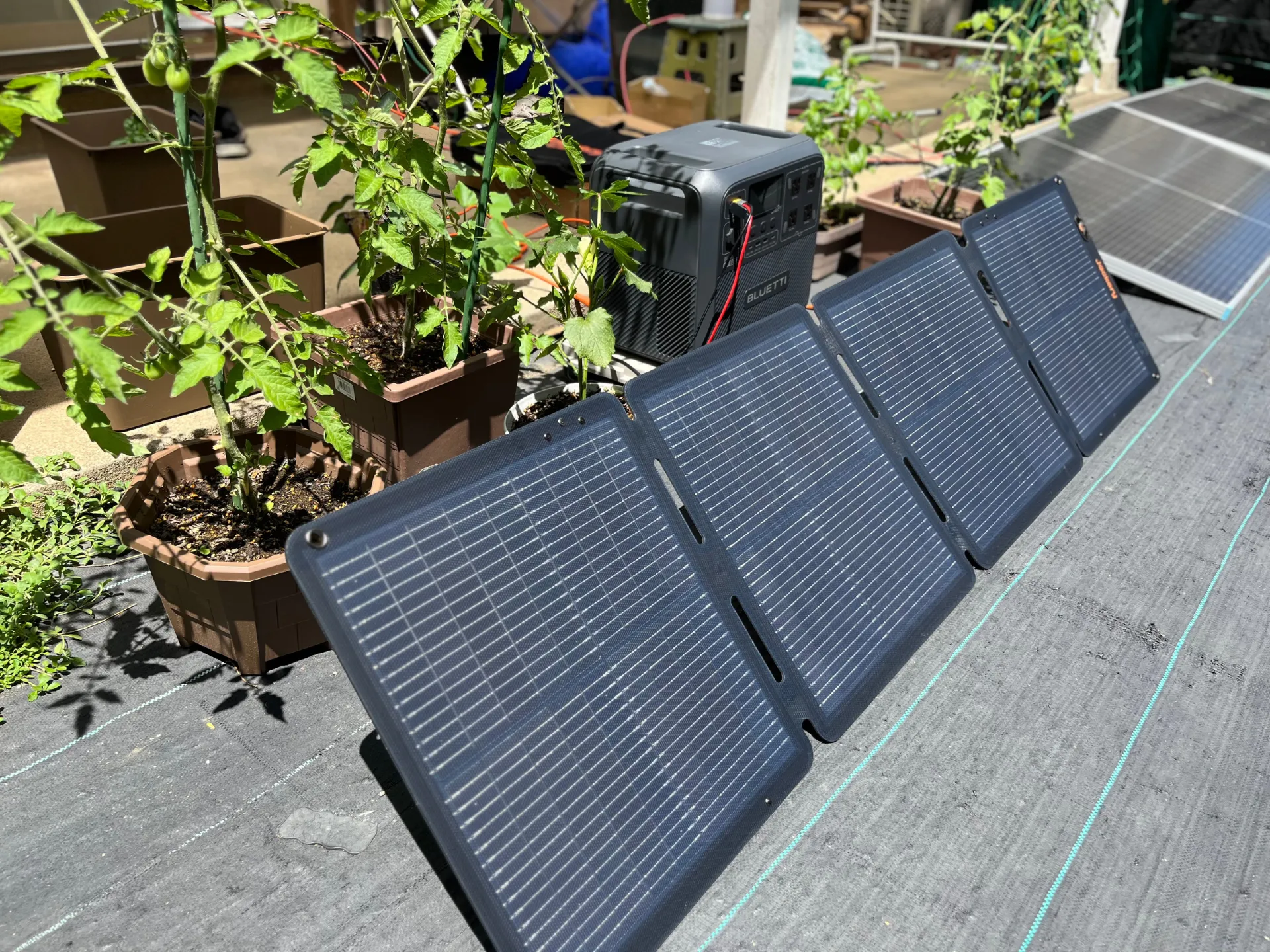ベランダ菜園の横に置かれた折りたたみソーラーパネルとポータブル電源